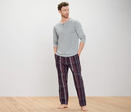 Gri pijama üstü ve dokuma altlı pijaması olan bir adam.