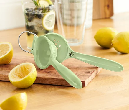 Limonların yanında tahta bir kesme tahtası üzerinde yeşil bir narenciye sıkacağı.
