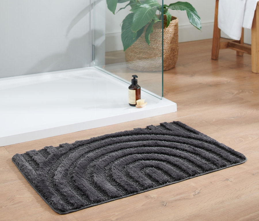 Antrasit rengi Wellness banyo paspası, yaklaşık 50 x 80 cm, ahşap bir zeminde duşakabinin yanında duruyor.