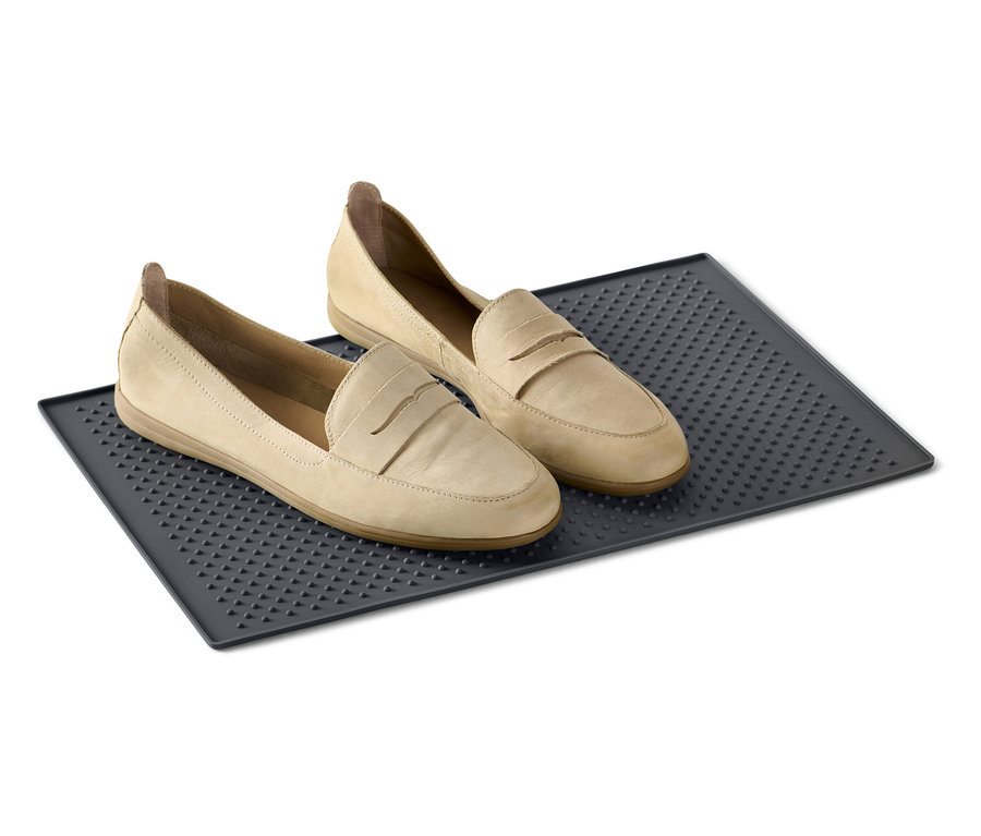 Üçgen desenli, koyu gri bir ayakkabı altlığının üzerinde iki adet bej rengi loafer ayakkabı duruyor.
