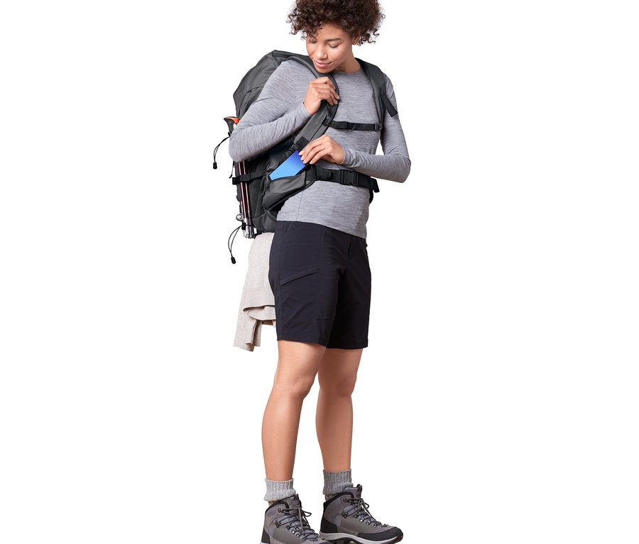 Kadın mavi telefonu 40 L'lik Trekking Sırt Çantasına koyuyor.