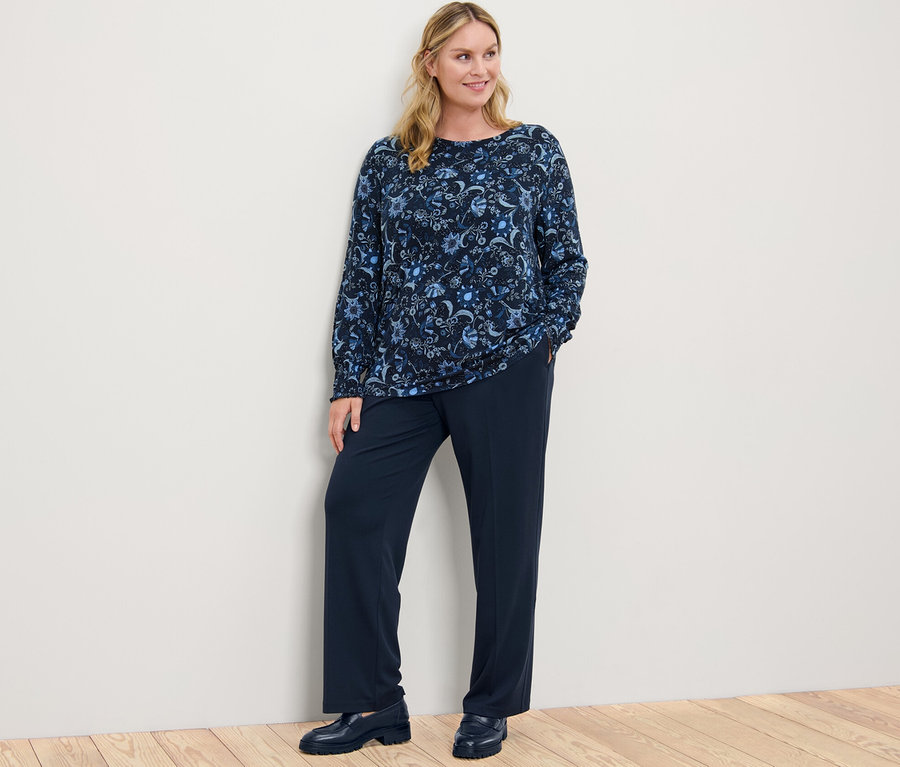 Kadın desenli bluz ve konforlu jarse pantolonla poz veriyor.