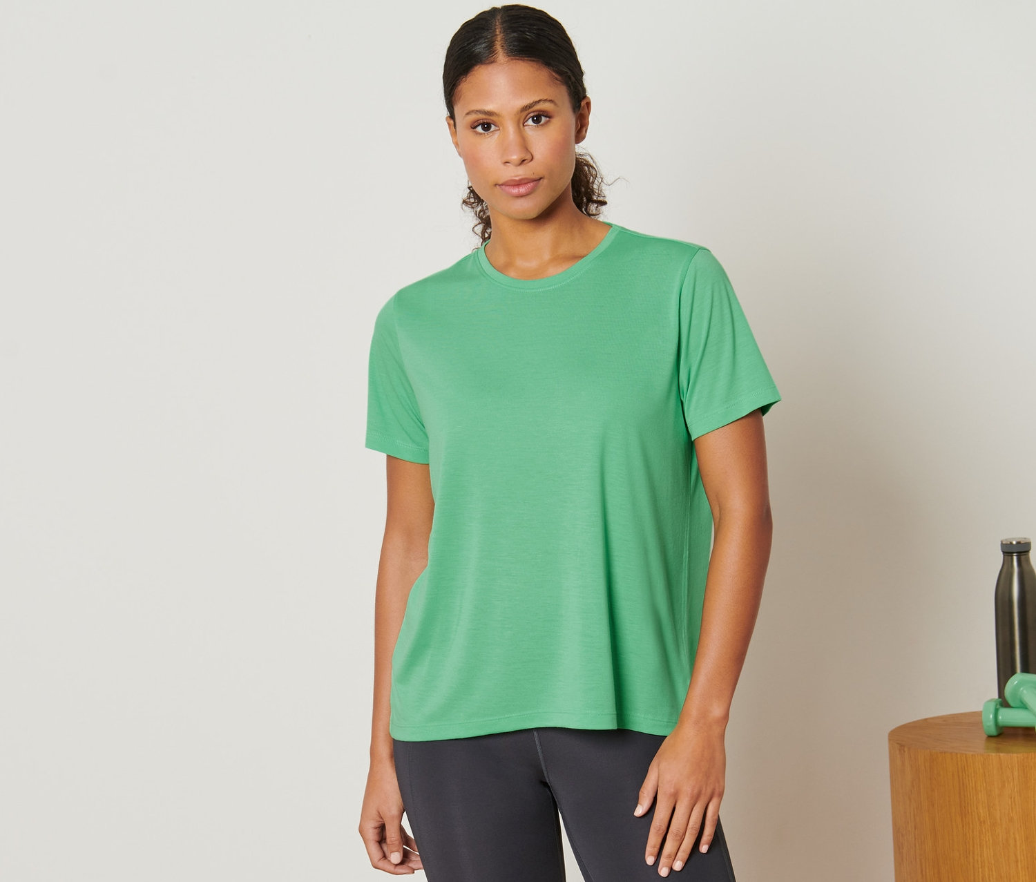 Kadın yeşil spor tişörtü giyiyor.