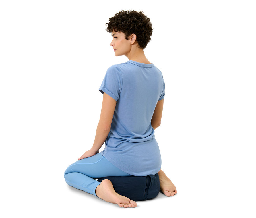 Kadın meditasyon minderinin üzerinde oturuyor.