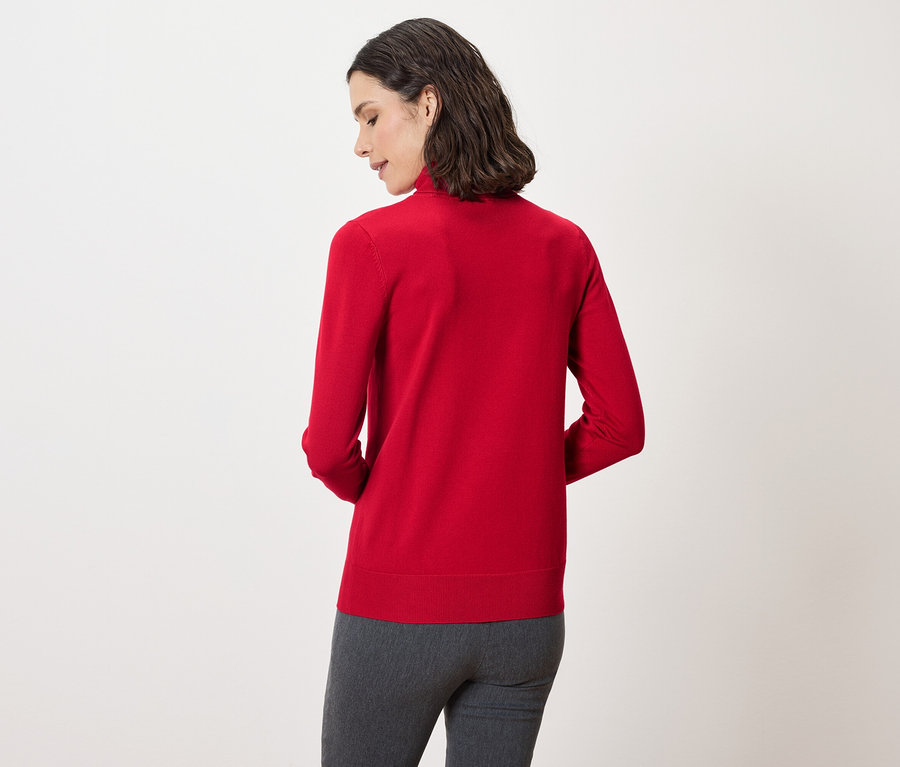 Arkadan koyu saçlı, kırmızı kazak ve gri pantolon giyen bir kadın görülüyor.