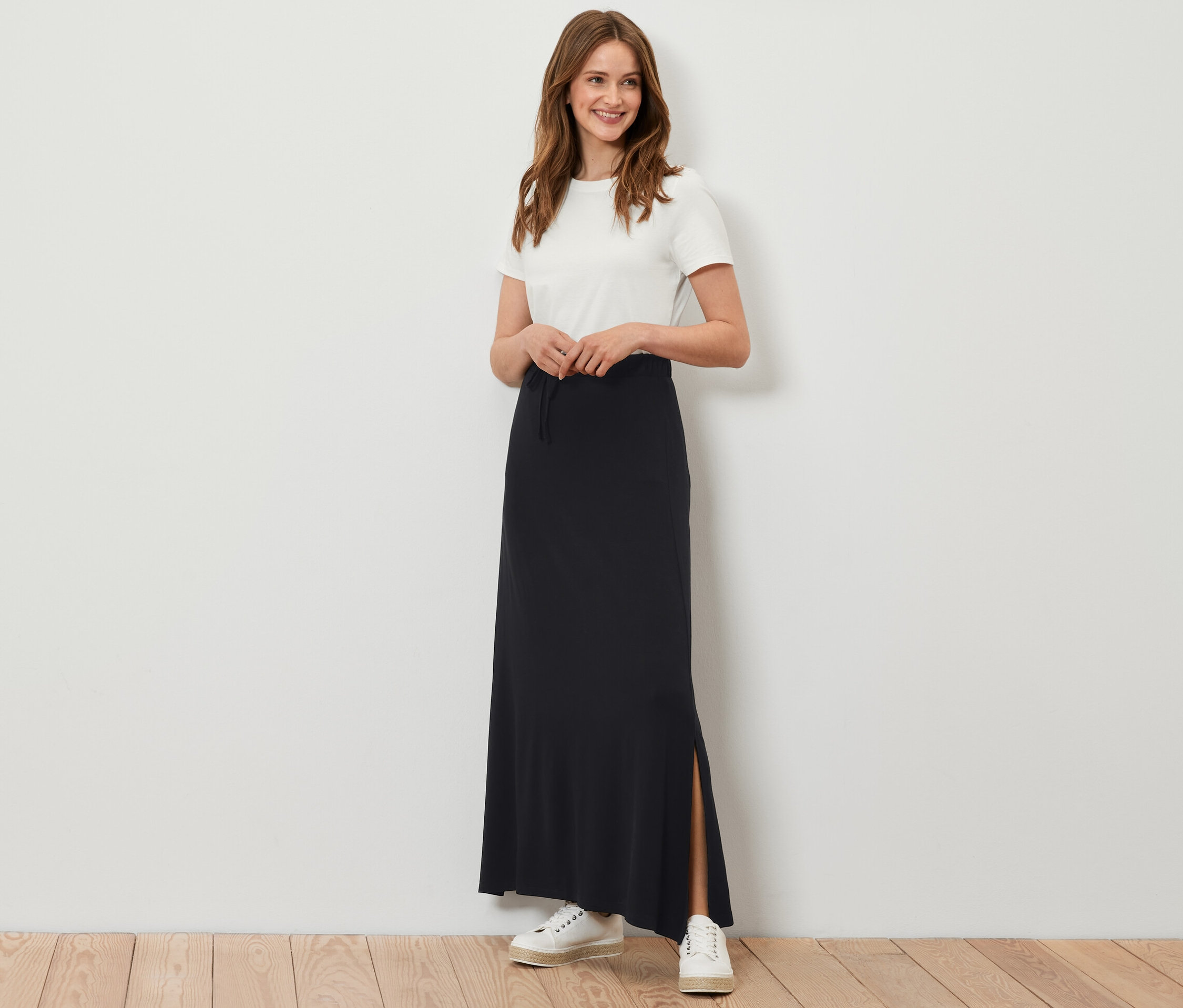 Kadın uzun siyah jarse etekle poz veriyor.