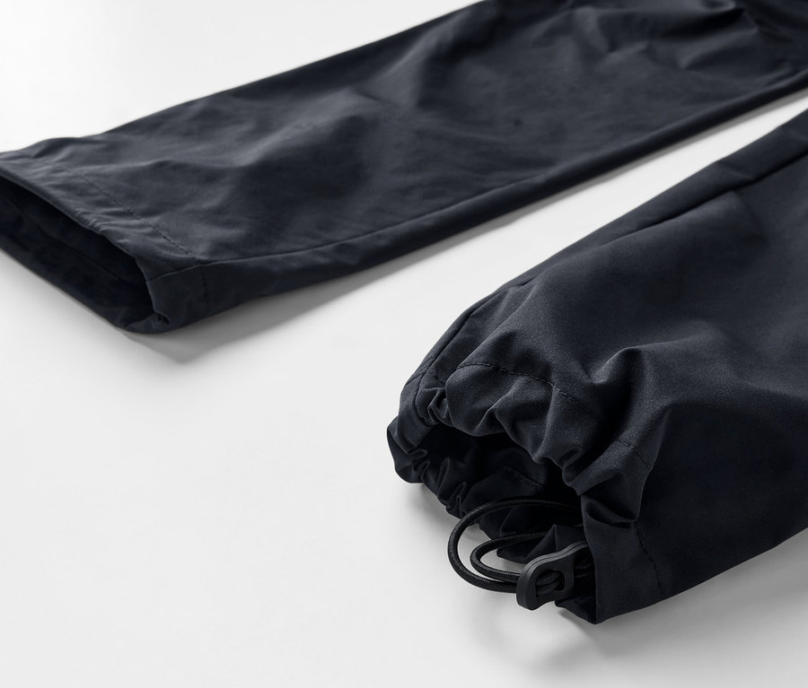 Paça kısmında büzme ipi bulunan siyah, 2'si 1 arada fonksiyonel pantolonun yakın çekim görüntüsü.