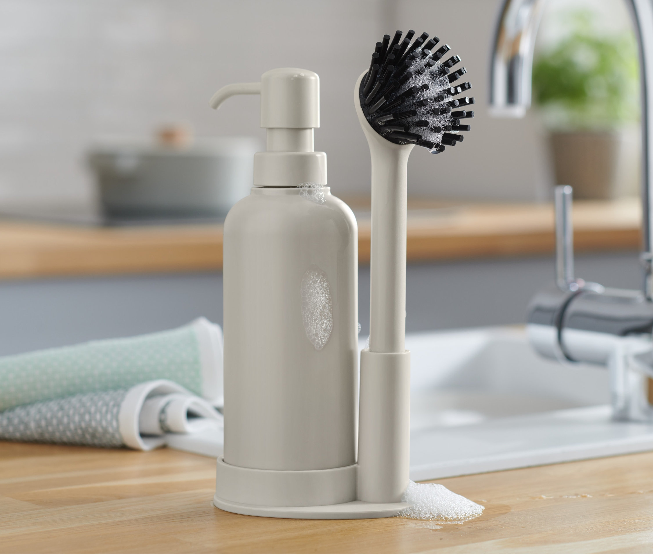 Tezgahta bulaşık deterjanı dispenseri ve fırçası bulunan bulaşık seti.