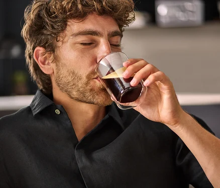 Adam çift cidarlı bardaktan kahve içiyor.