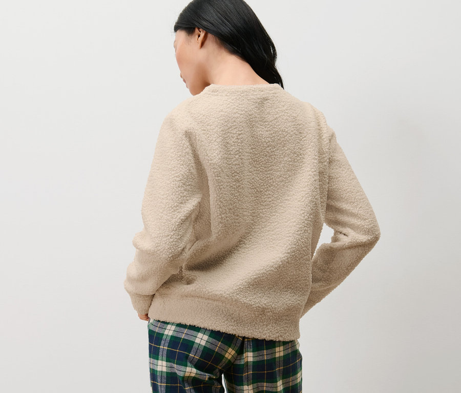 Arkası dönük bir kadın pelüş kazak ve kareli pantolon giyiyor.