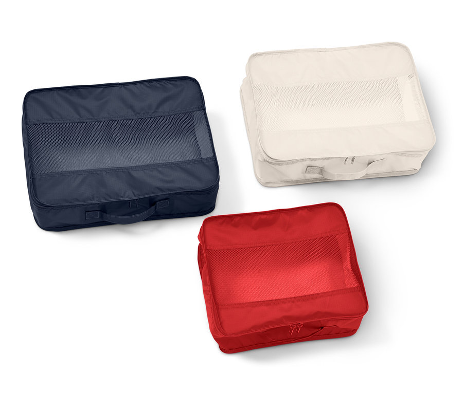 Üzerinde file pencere bulunan lacivert, krem ve kırmızı renklerde üç adet dikdörtgen kumaş bavul düzenleyici.