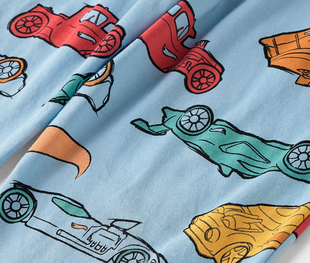 Açık mavi kumaş üzerine renkli araba baskısı.