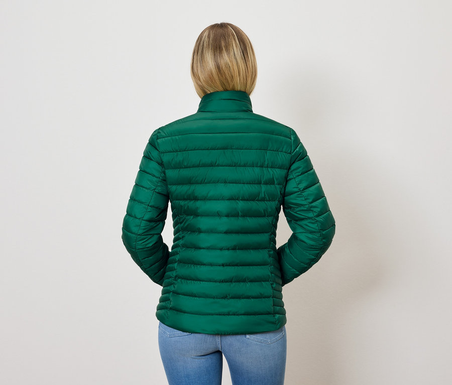 Arkadan, sarı saçlı, yeşil kapitone ceket ve mavi kot pantolonlu bir kadın manzarası.