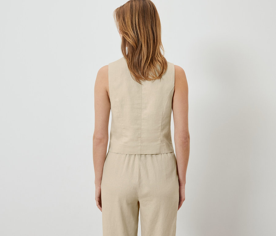 Arkadan keten yelek ve pantolon giyen bir kadın görülüyor