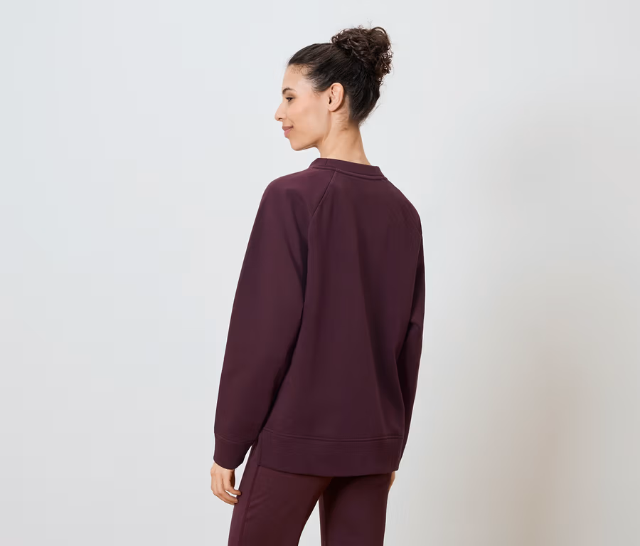 Arkadan bordo renkli bir sweatshirt ve uyumlu pantolon giyen kadın.