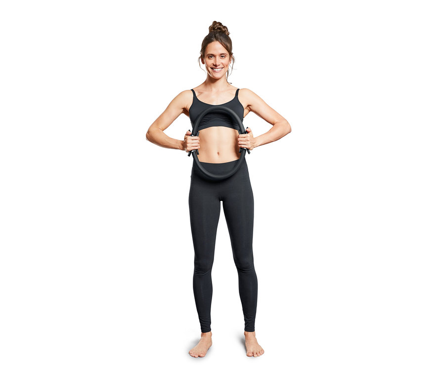 Kadın siyah bir Pilates Halkası tutuyor.