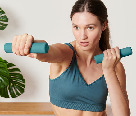 Kadın 2 adet dambılla egzersiz yapıyor