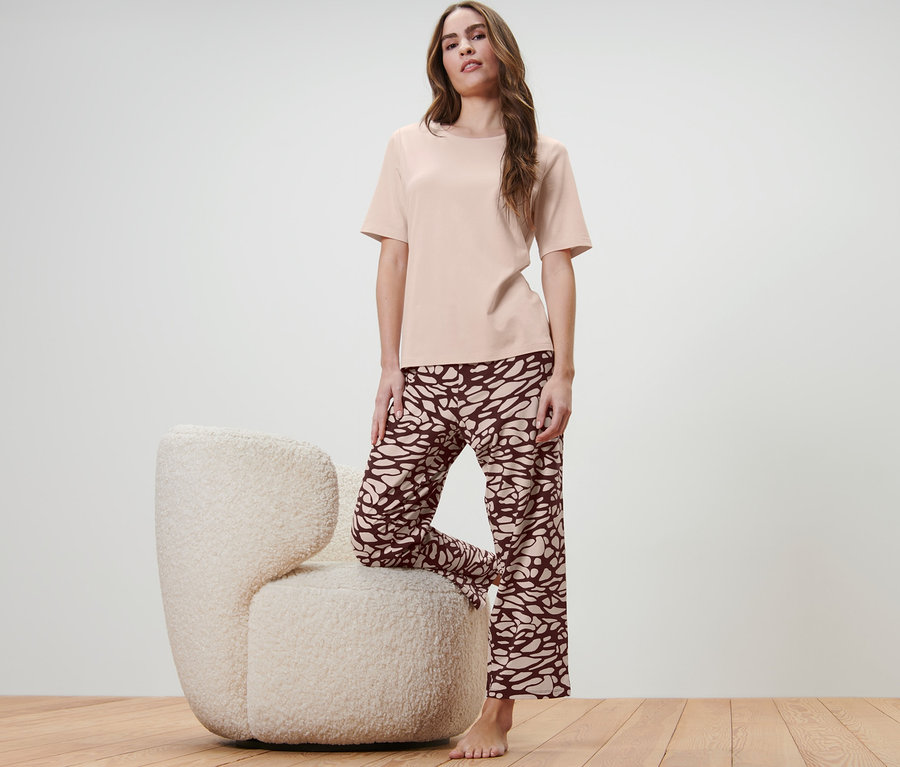 Kadın tüylü bir koltukta tek bacağı ile poz veriyor ve Pijama Takımı giyiyor.