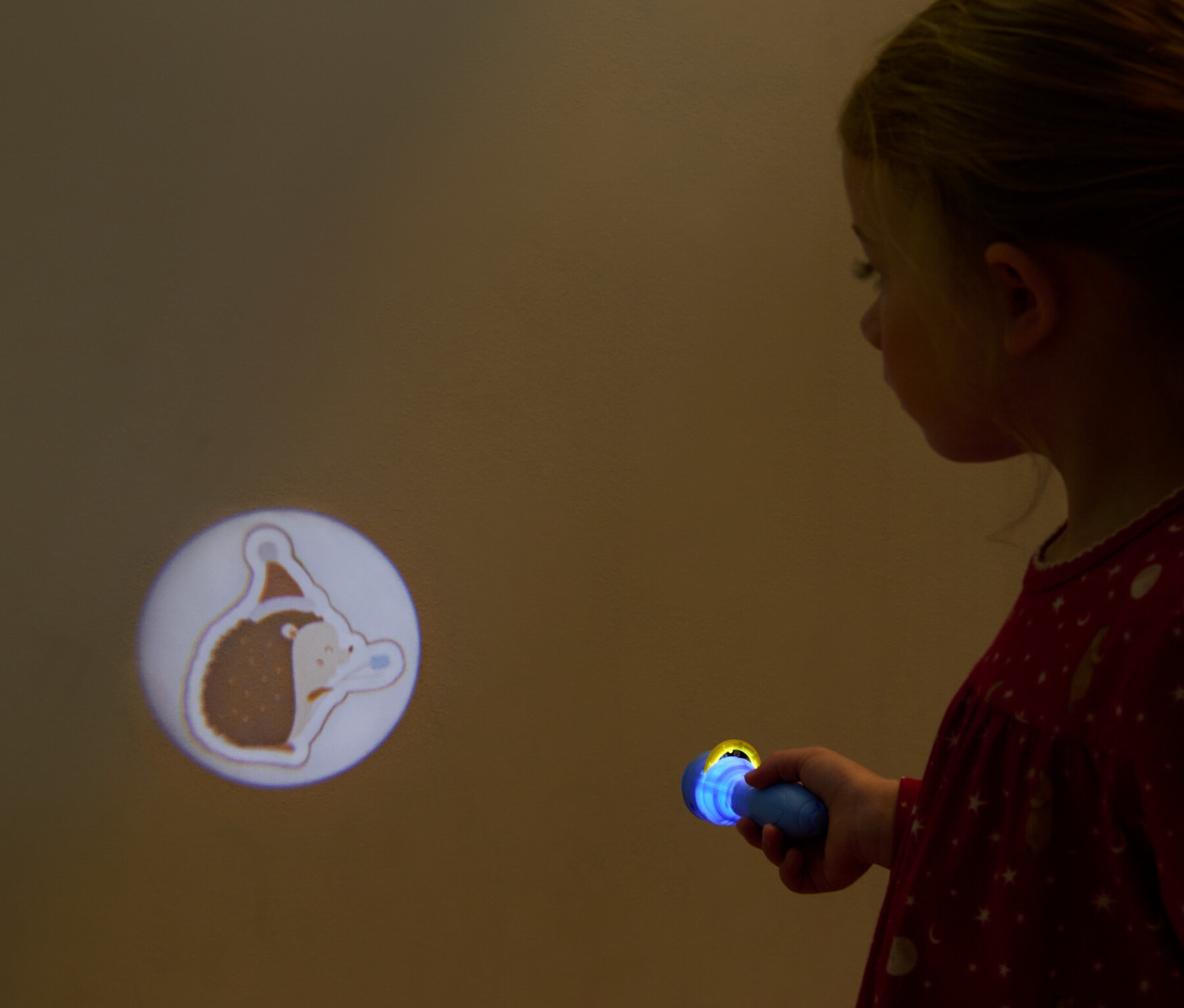 Kız, duvara Projektör El Feneri ile Noel şapkalı bir kirpi resmi yansıtıyor: "Kış Hayvanları".