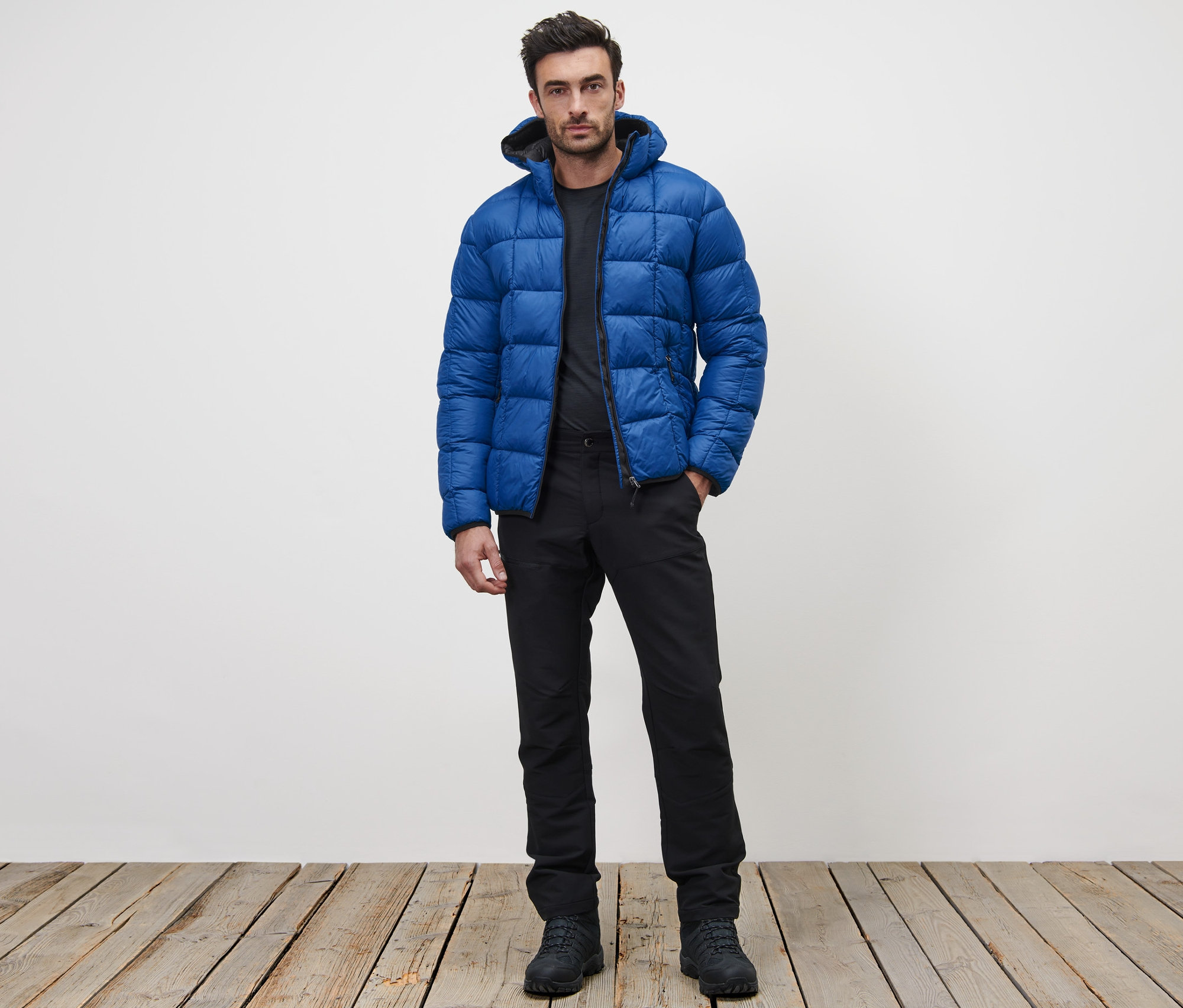 Adam ayakta duruyor ve mavi kapitone mont giyiyor.