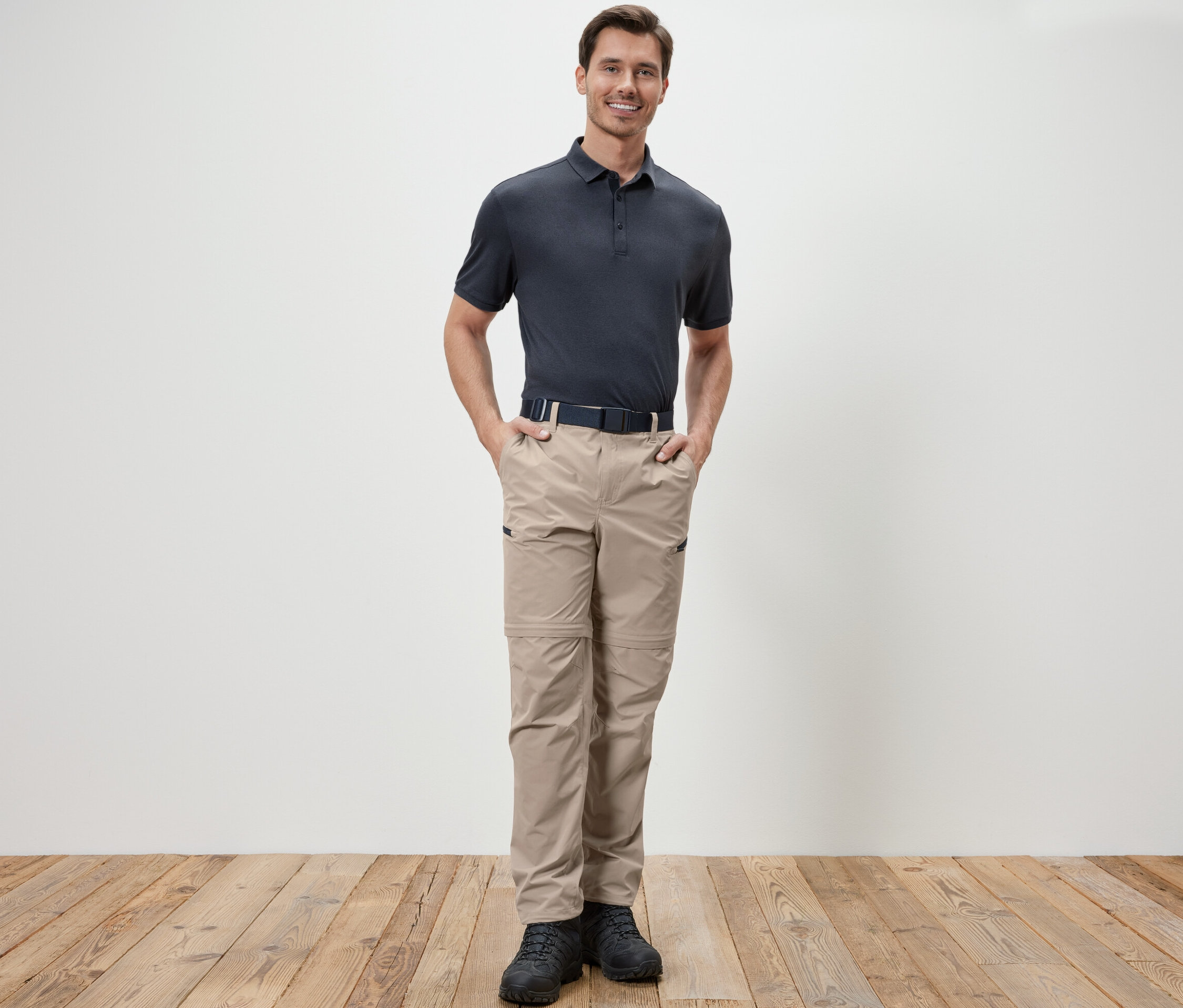 Bir adam bej rengi 2'si 1 arada fonksiyonel pantolonun cebinde elleriyle duruyor.