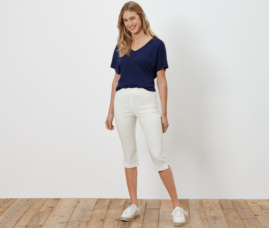 Kadın beyaz 3/4 streç pantolonla poz veriyor.