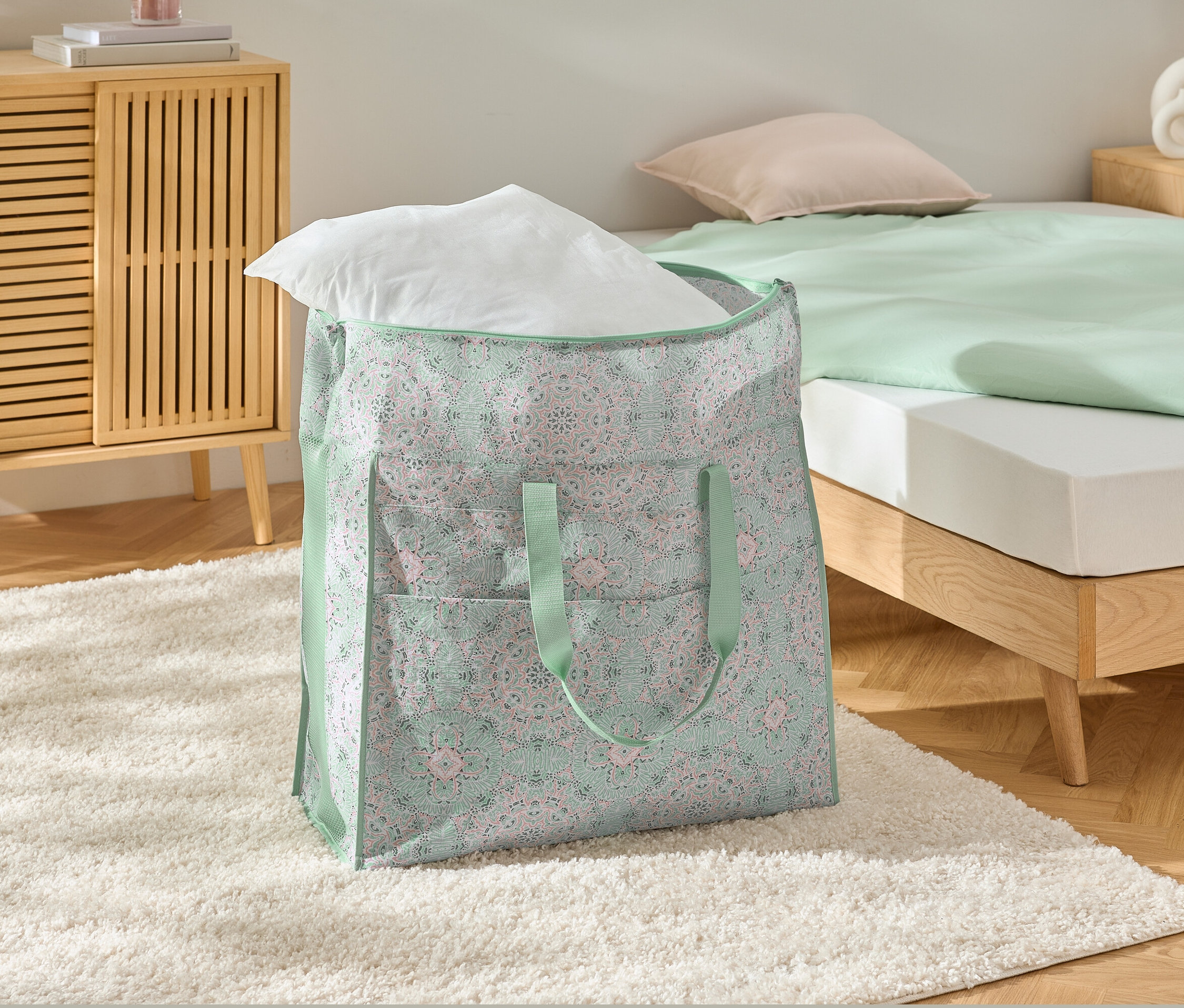 Beyaz halı üzerinde beyaz yastıklı büyük bir yatak saklama çantası.