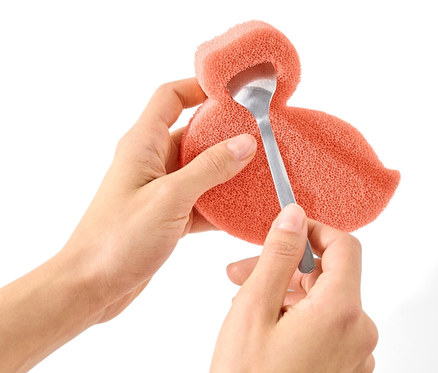 Eller bir silikon süngeri tutuyor ve bir kaşıkla içine batırıyor.