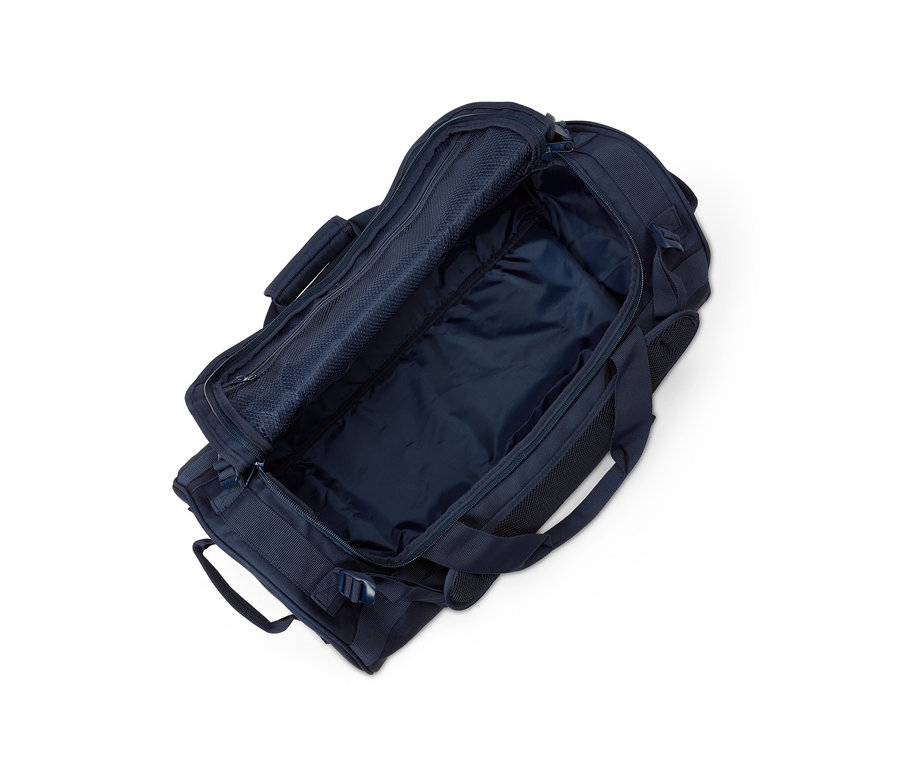 Beyaz bir arka plan üzerinde açık, lacivert bir seyahat çantası ve sırt çantası.