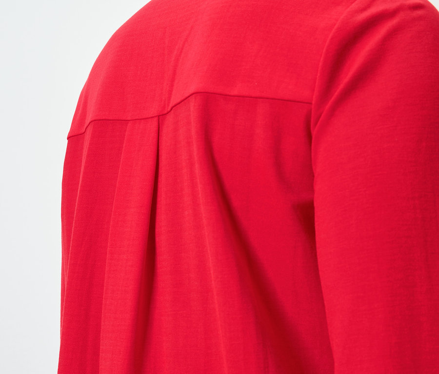 Pileli, kırmızı, uzun kollu bir gömleğin arka kısmının yakın çekimi