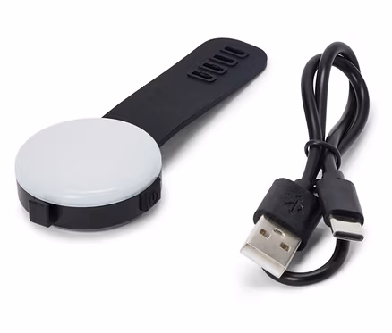 Beyaz bir arka plan üzerinde siyah saplı, siyah, yuvarlak bir LED ışığı ve bir USB kablosu duruyor.