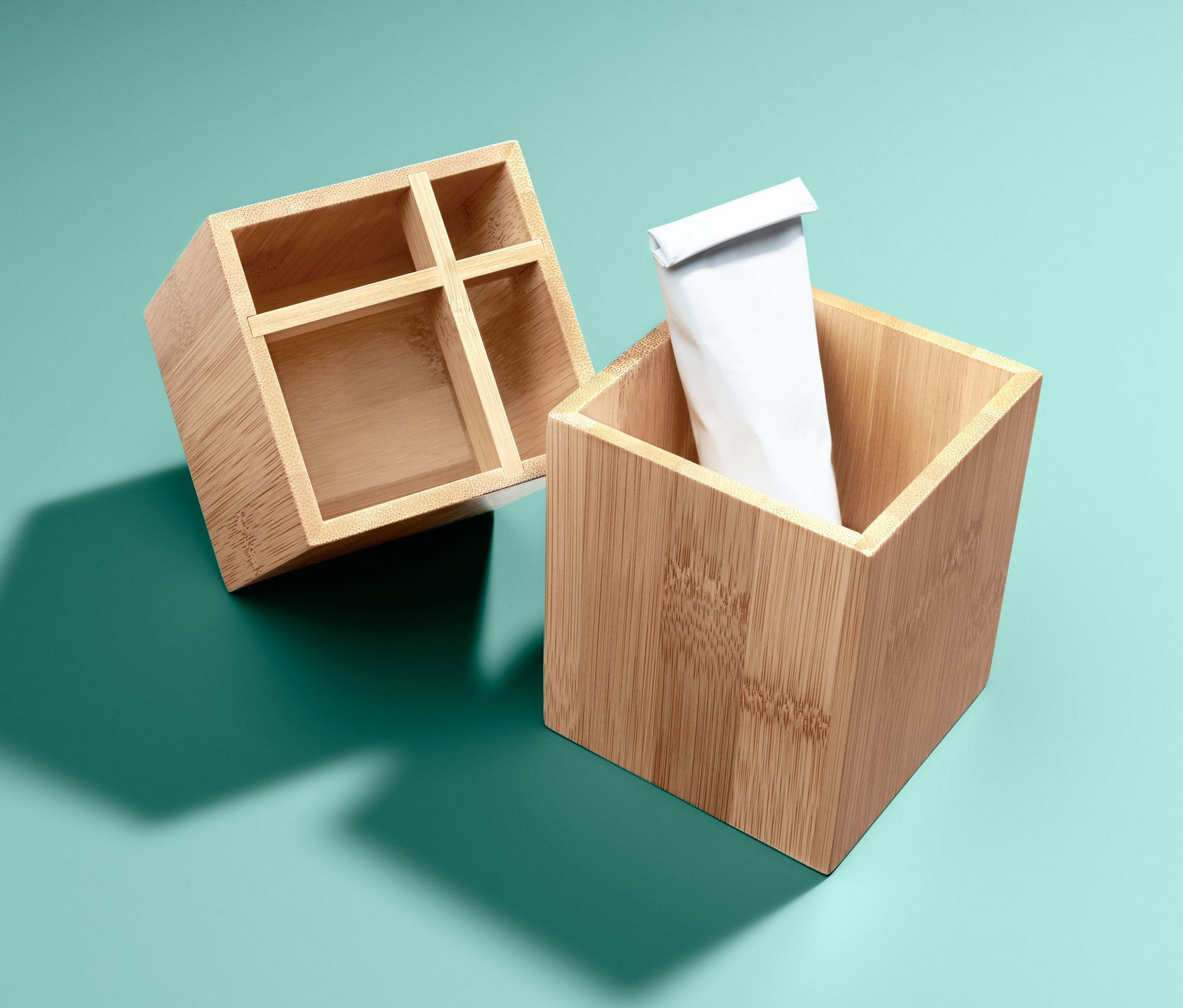 Turkuaz zemin üzerinde iki adet bambu düzenleyici, biri boş, diğeri beyaz tüplü.