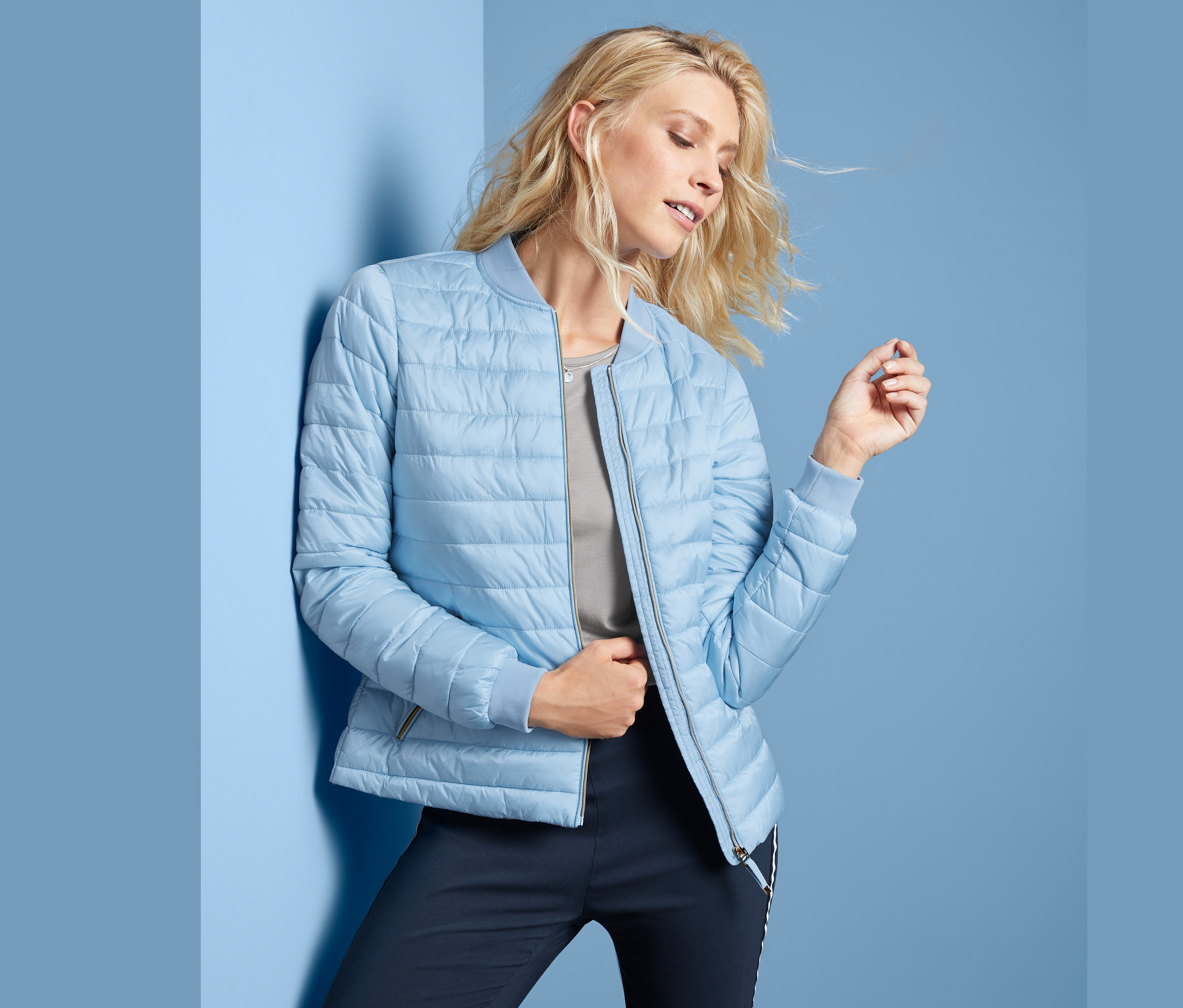 Sarışın kadın mavi kapitone mont giyiyor.