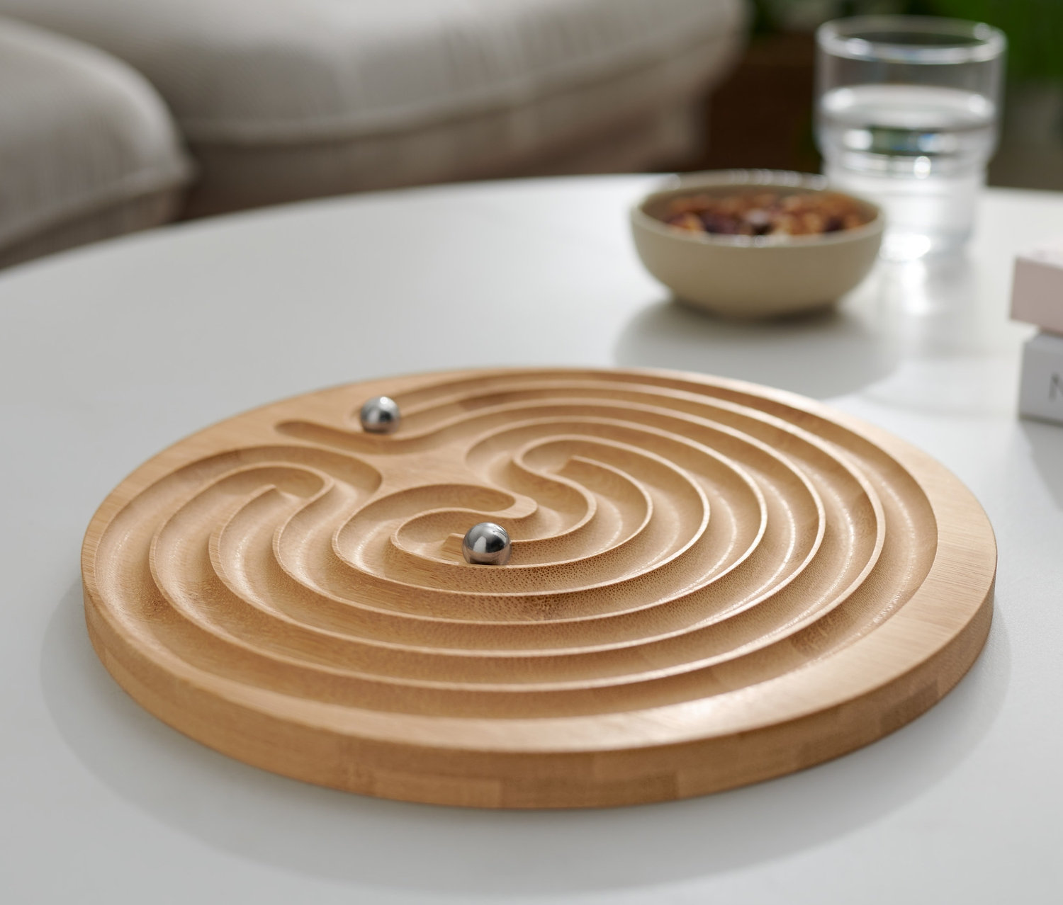 Beyaz bir masanın üzerinde iki bilyeli bir "Labirent" Sabır Oyunu duruyor.