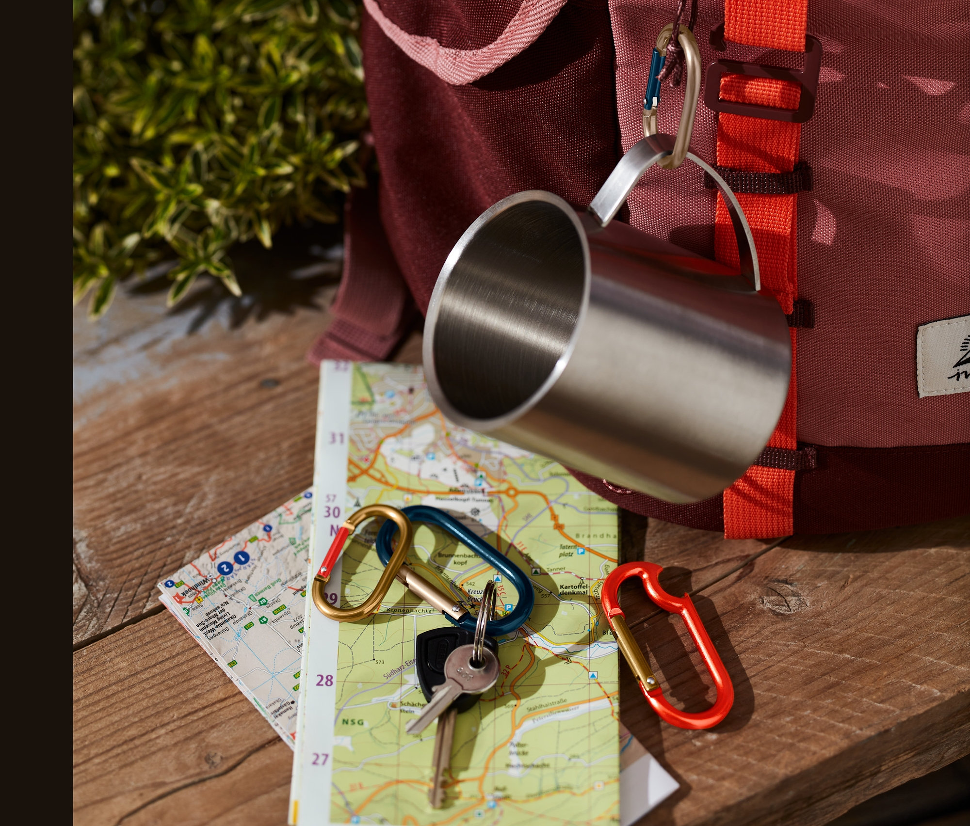 Dört adet karabina, bir harita üzerinde sırt çantasının yanında duruyor.