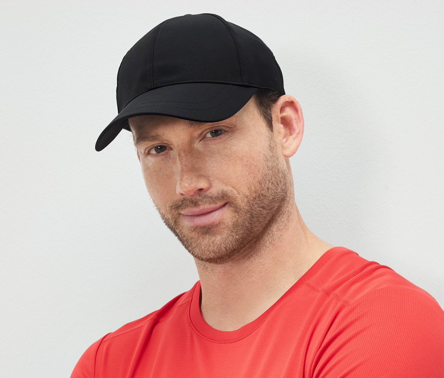 Kollarını kavuşturmuş bir adam siyah spor şapka takıyor.