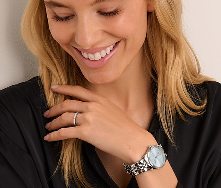 Gülümseyen kadın, Tarihli Paslanmaz Çelik Kol Saatine ve yüzüğüne bakıyor.