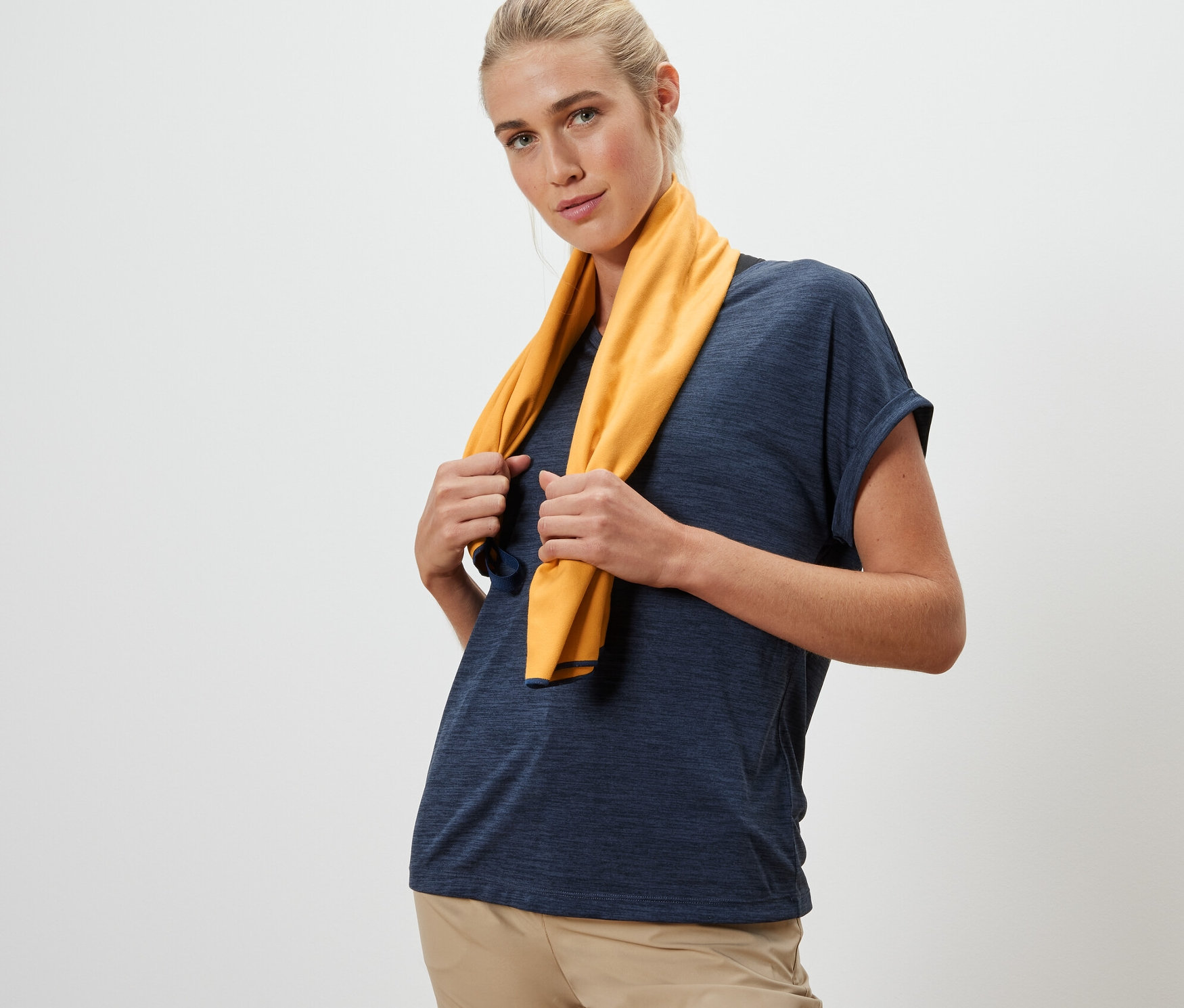 Kadın boynunda sarı renkli, yaklaşık 50 x 100 cm boyutlarında bir outdoor havlu tutuyor.