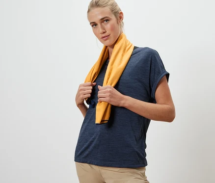 Kadın boynunda sarı renkli, yaklaşık 50 x 100 cm boyutlarında bir outdoor havlu tutuyor.