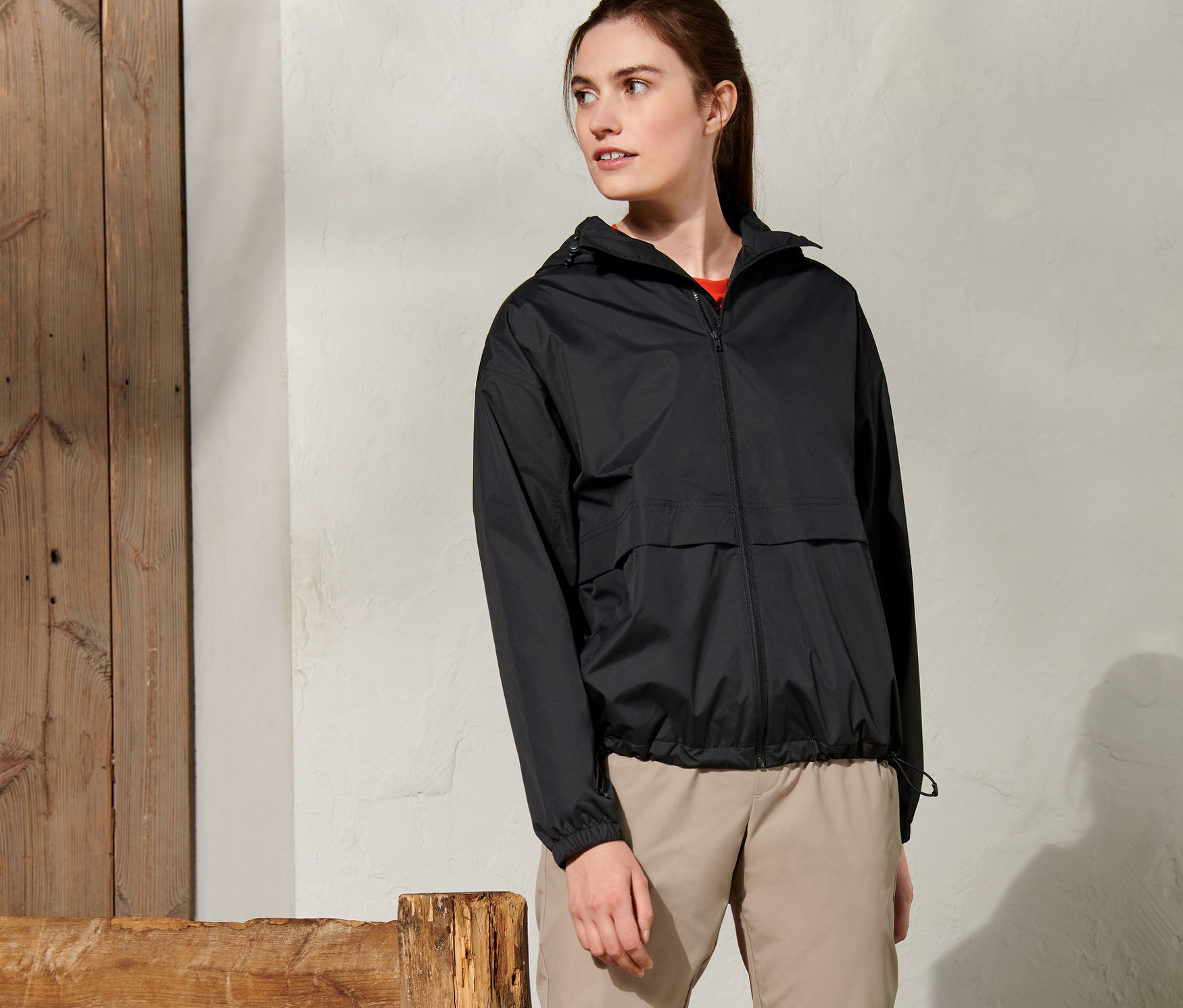 Kadın dışarıda duruyor ve siyah bir yağmurluk giyiyor.