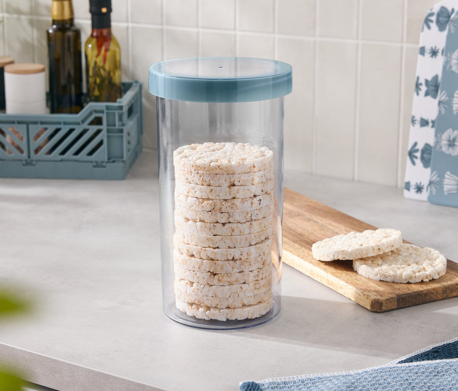 Mavi kapaklı bir kapta istiflenmiş pirinç kekleri var, iki tane daha tahta bir tahtanın üzerinde duruyor.