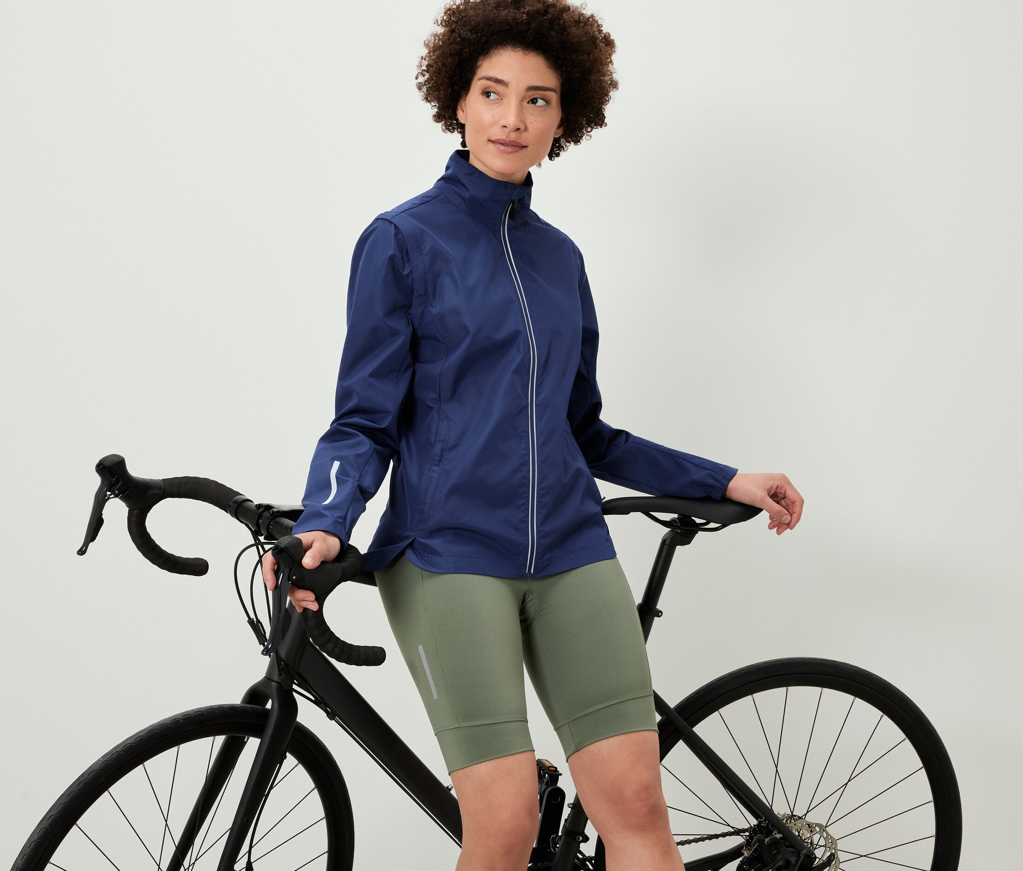 Bisikletine yaslanan kadın, 2'si 1 Arada Bisiklet Montu giyiyor.