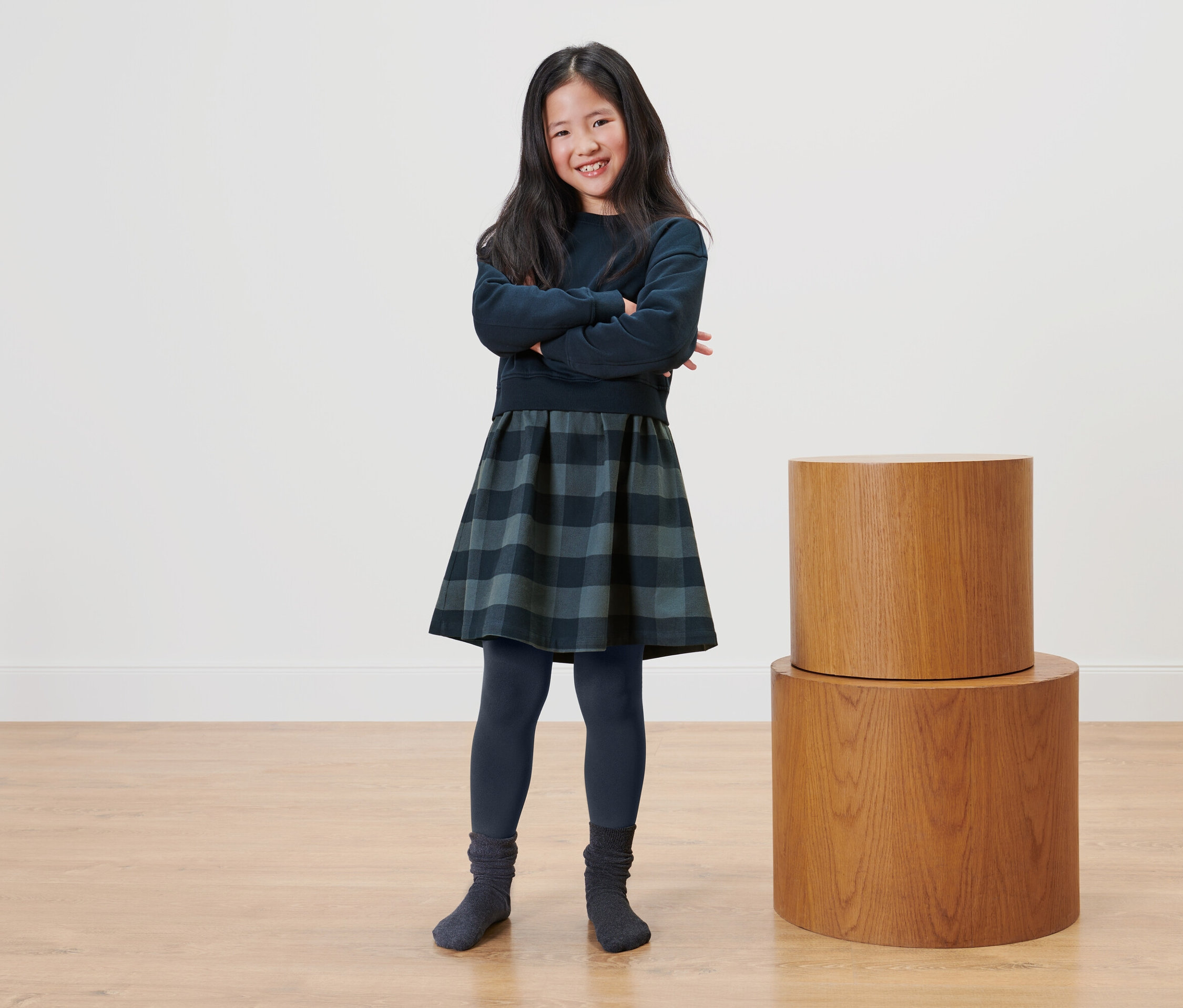 Kolları çapraz kız, iki ahşap sehpanın yanında duruyor.