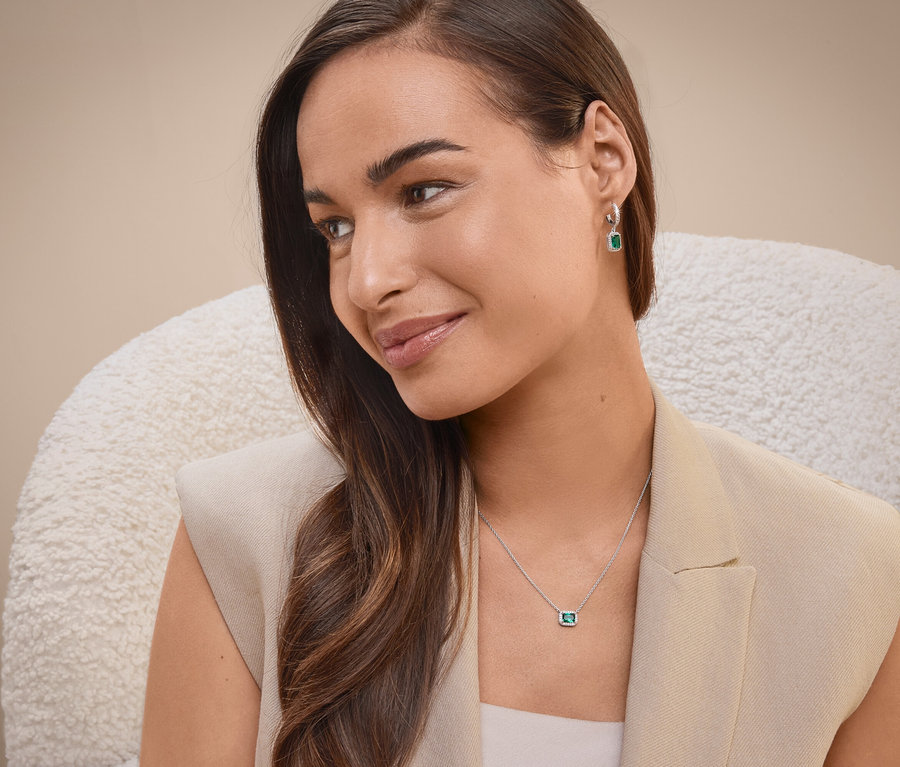 Bir kadın sandalyede oturuyor, kolye ve küpe takıyor.