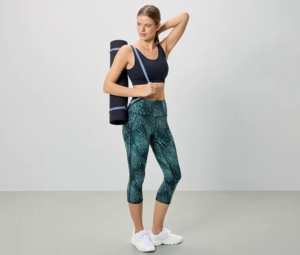 Omzunda yoga matı olan spor giyimli kadın.