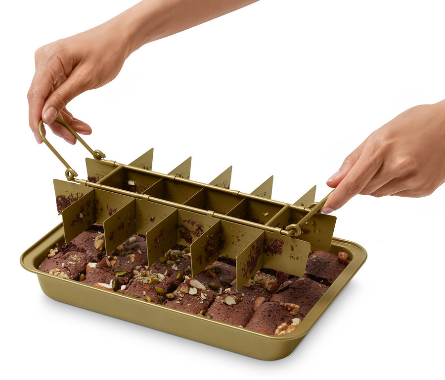 Bir kişi, kesilmiş brownieler bulunan bir fırın tepsisinin üzerinde bir Brownie Pişirme Kalıbı tutuyor.