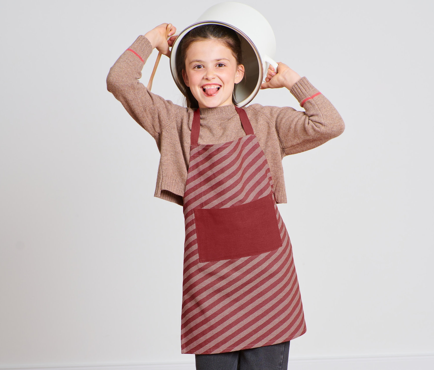 Kafasında tencere olan çocuk, çocuk önlüğü takıyor.