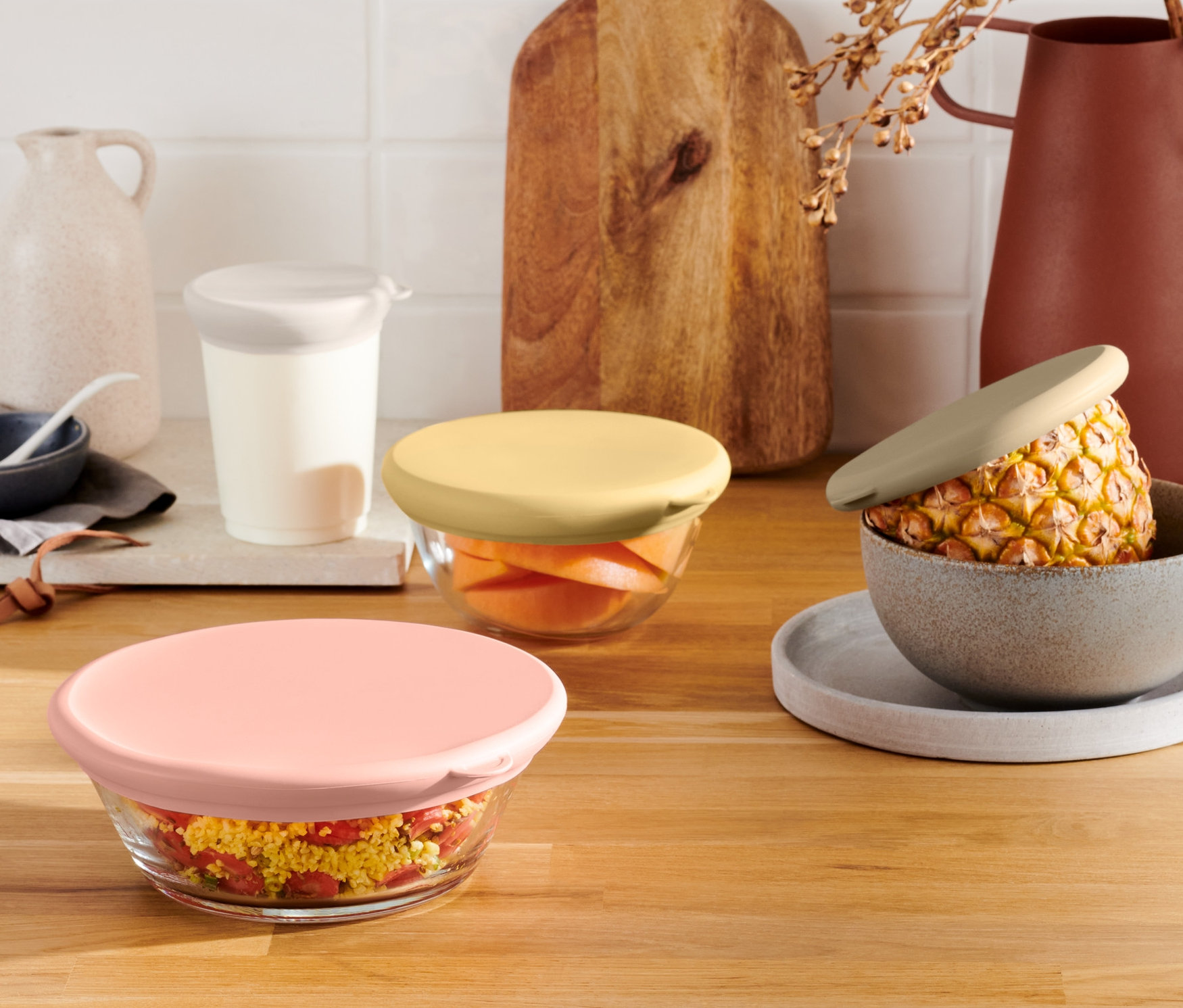 Ahşap bir masanın üzerinde renkli 4 Adet Taze Tutan Silikon Kapaklı cam kaseler.