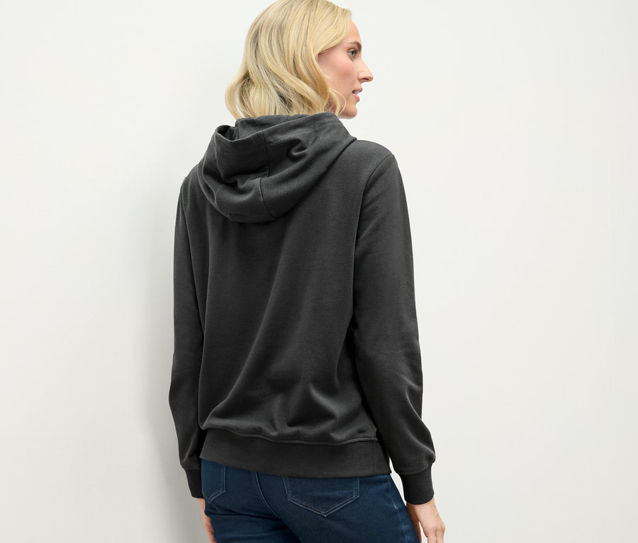 Antrasit rengi kapüşonlu bir sweatshirt giyen sarışın bir kadının arka görünümü.