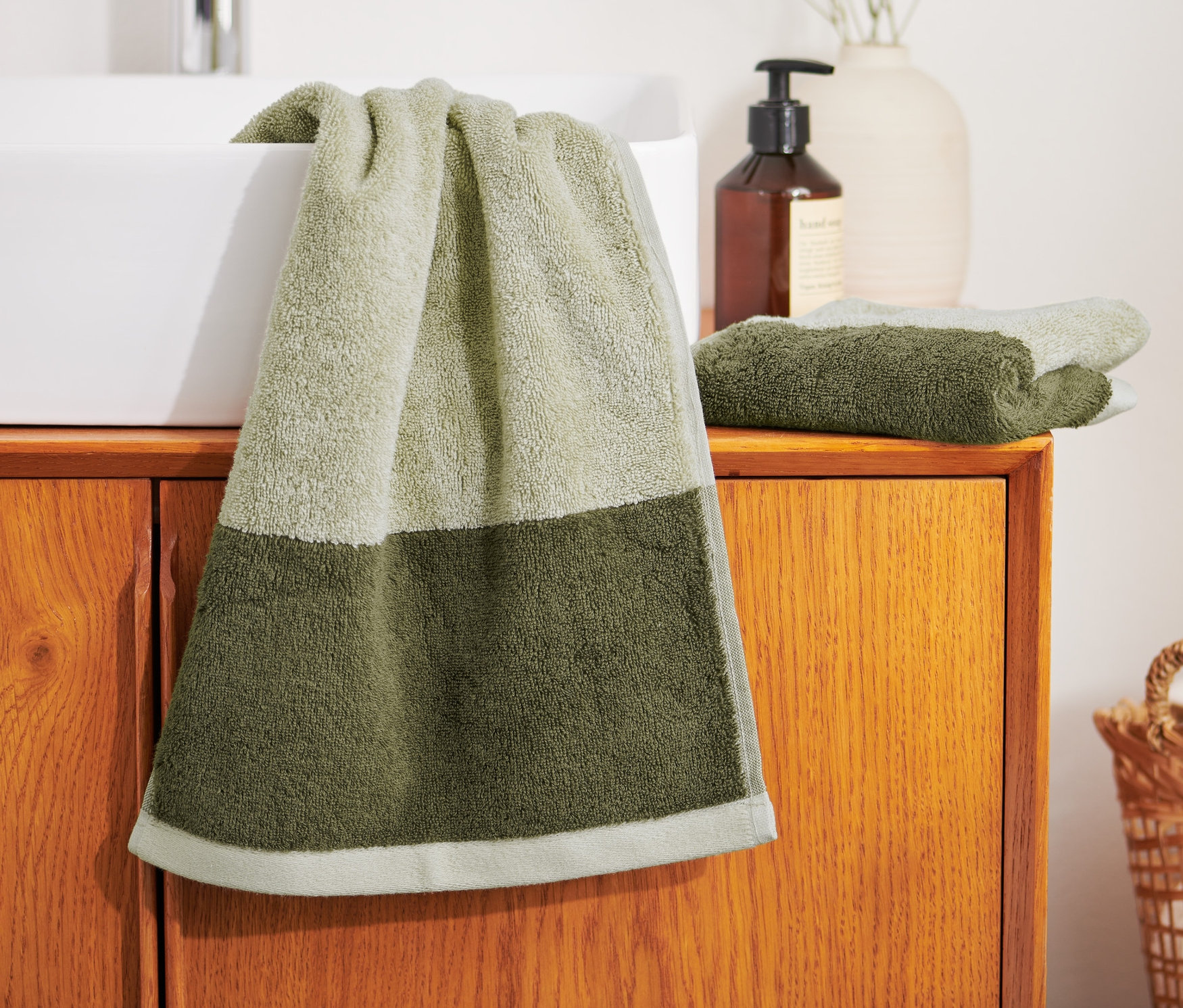 Yeşil bir havlu lavabonun üzerinde asılı duruyor, yanında 2 adet yüksek kaliteli jakar misafir el havlusu bulunmaktadır.